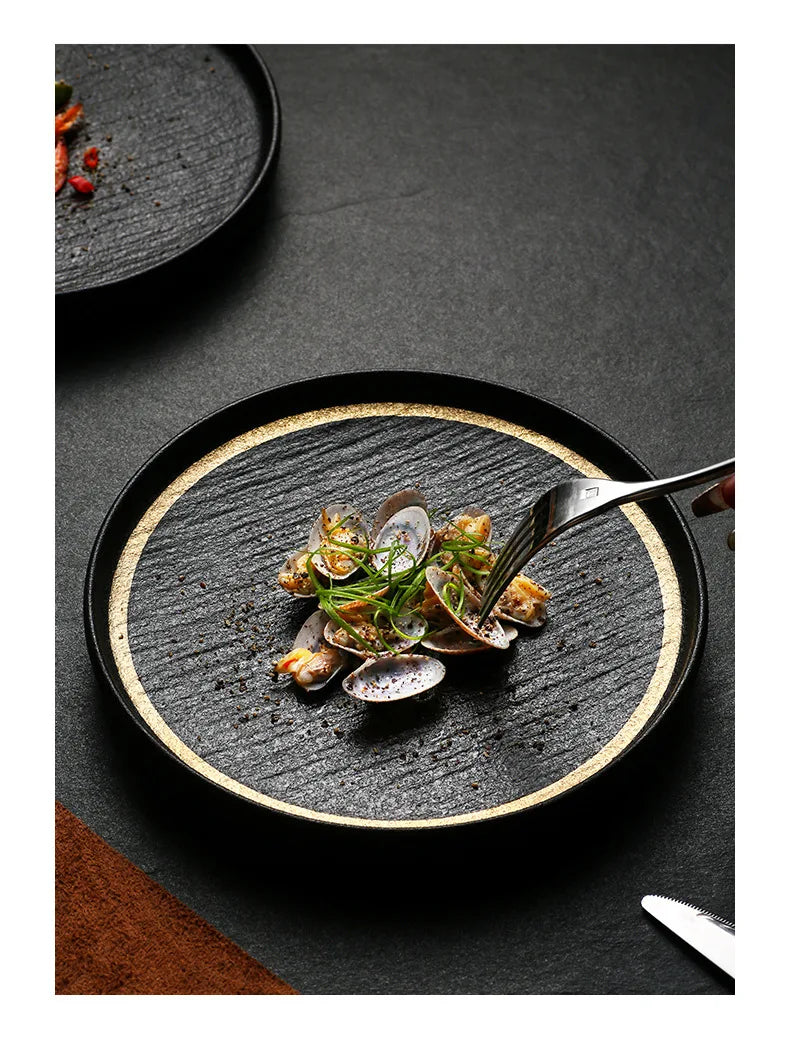 A black slate plate with a gold rim, perfect for serving appetizers or desserts.