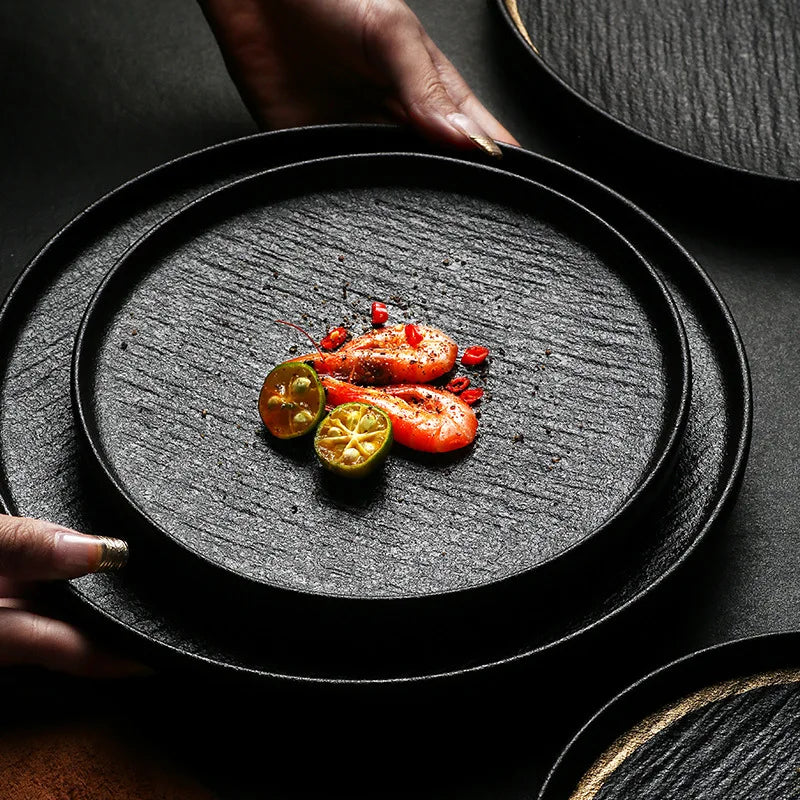 A black slate plate with a gold rim, perfect for serving appetizers or desserts.