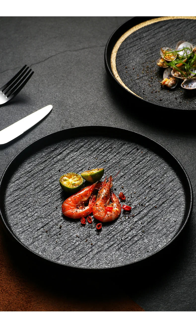 A black slate plate with a gold rim, perfect for serving appetizers or desserts.