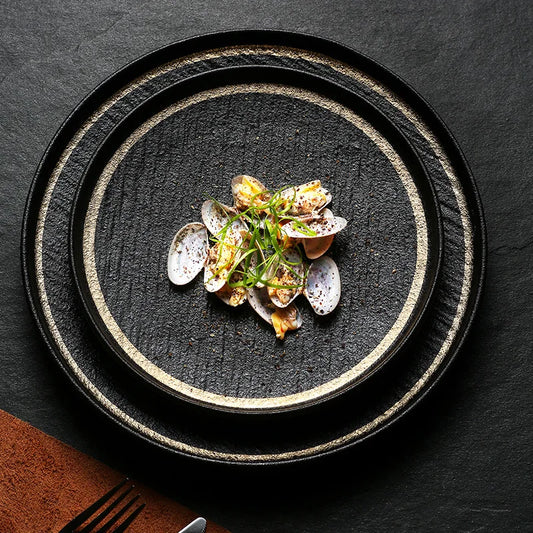 A black slate plate with a gold rim, perfect for serving appetizers or desserts.