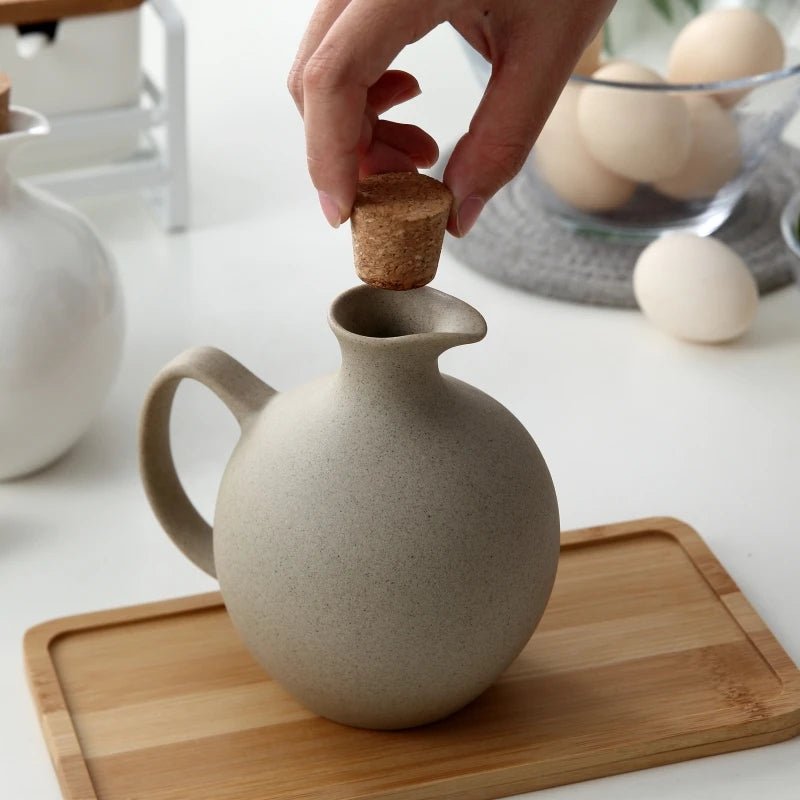 A person opening a ceramic oil bottle, with one hand holding a wooden lid