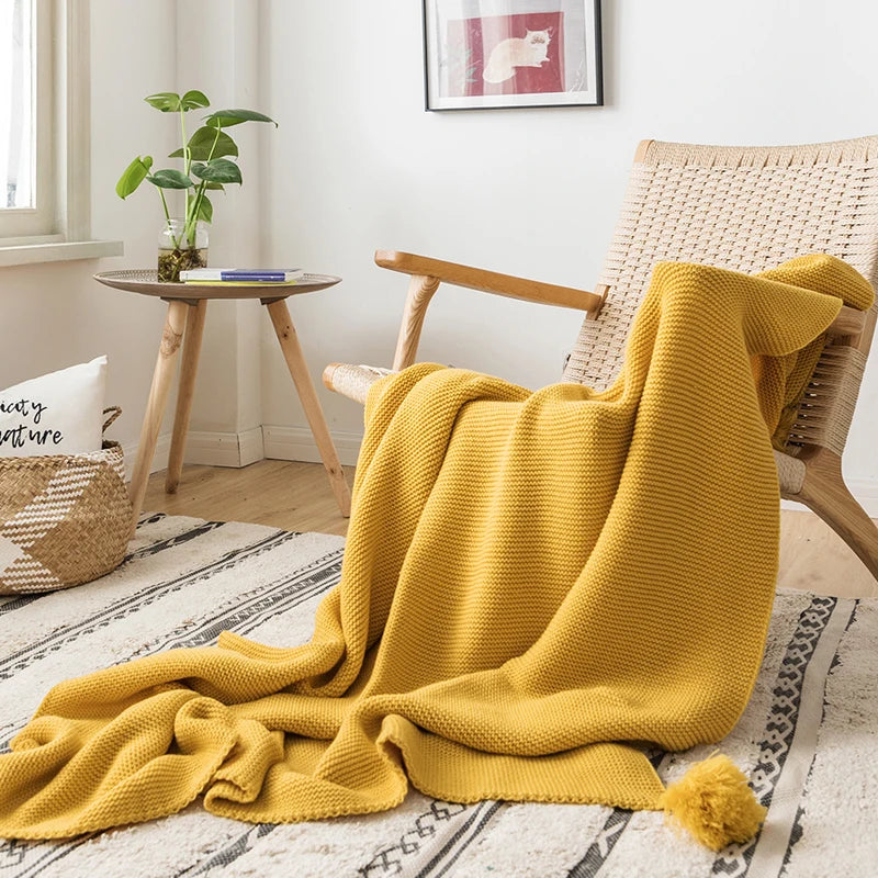 A cozy knitted blanket in a luxurious design draped over a chair.