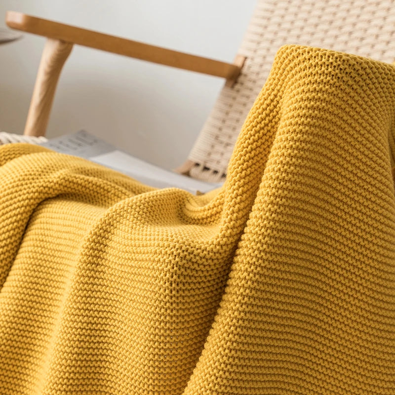 A cozy knitted blanket in a luxurious design draped over a chair.