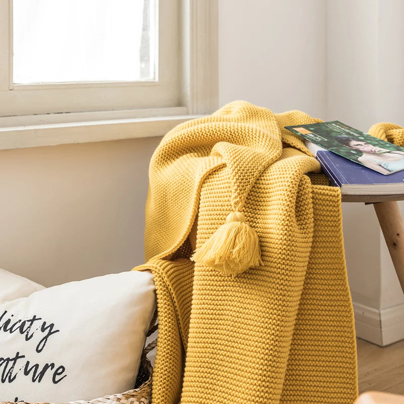 A cozy knitted blanket in a luxurious design draped over a chair.