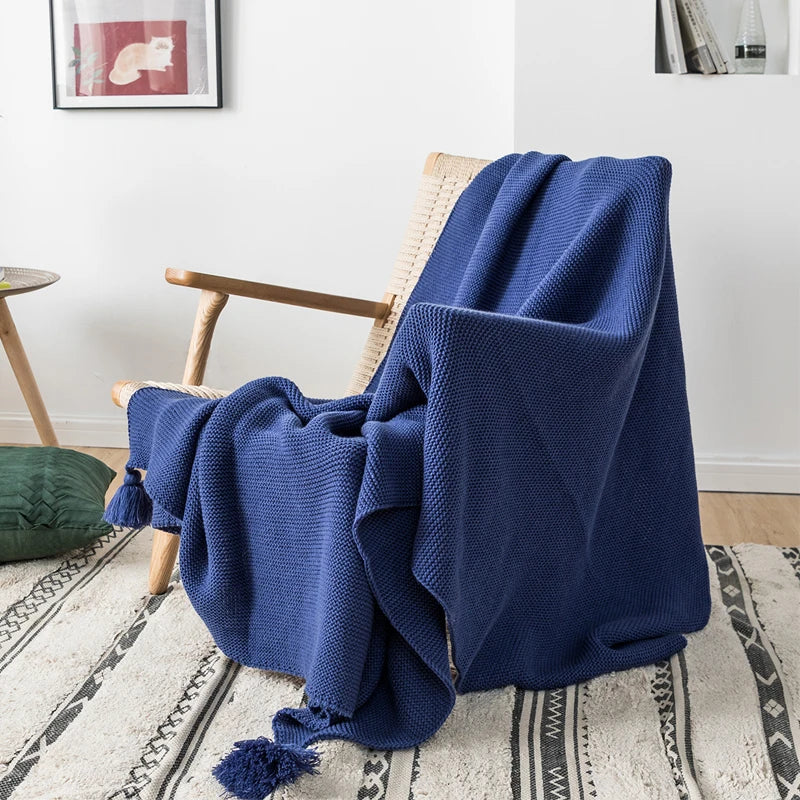 A cozy knitted blanket in a luxurious design draped over a chair.