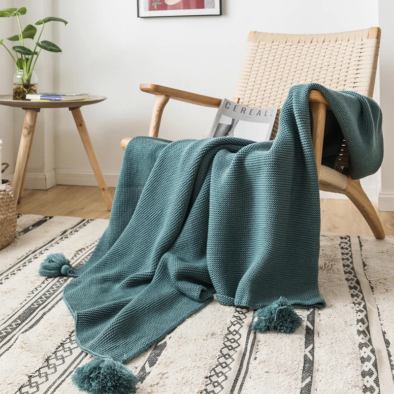 A cozy knitted blanket in a luxurious design draped over a chair.