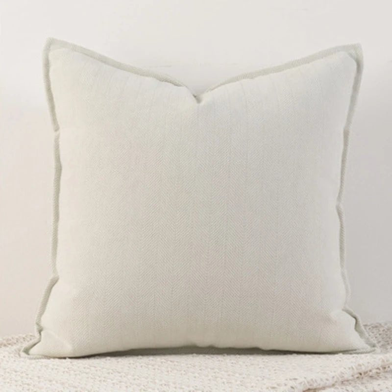 A cream Nordic cushion cover placed over a couch, showcasing its delicate and cozy texture.