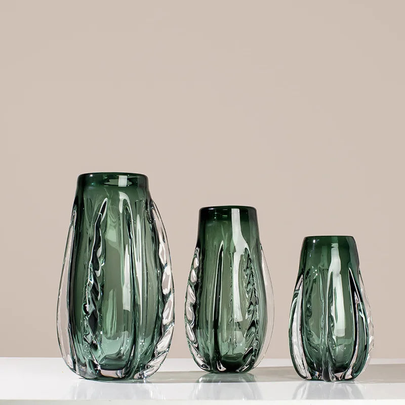 A green crystal vase with a sleek design for flowers or home decor.