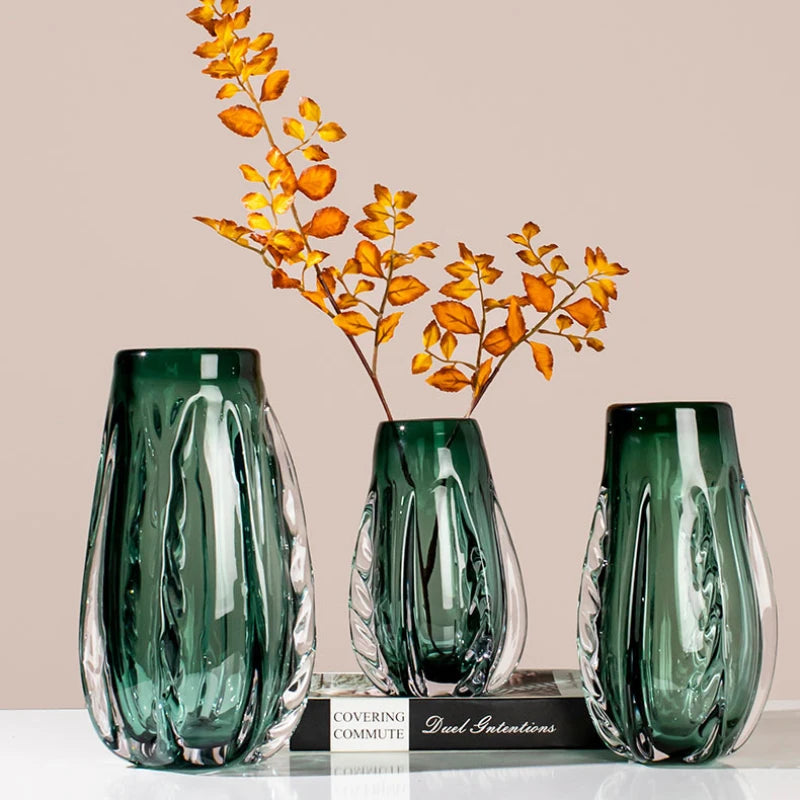 A green crystal vase with a sleek design for flowers or home decor.