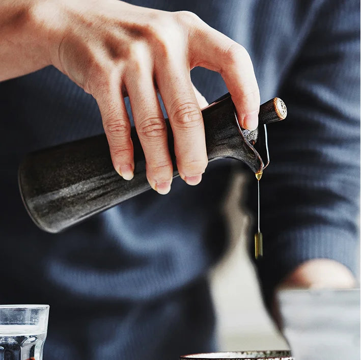 A gray vintage ceramic oil and vinegar dispenser with a classic design and decorative details