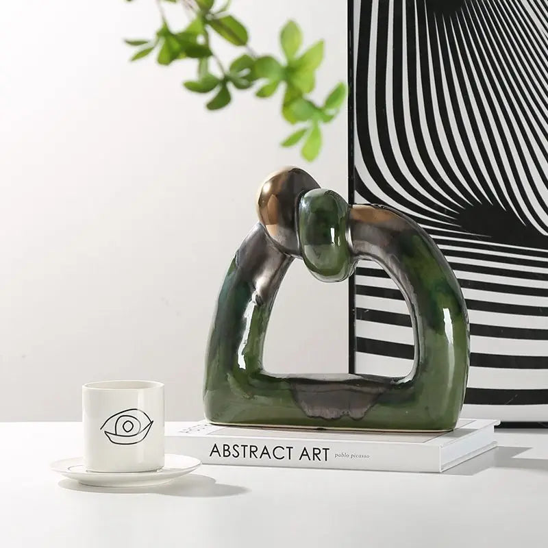 Green and silver abstract knot ceramic sculpture with hollow geometric design, perfect for modern home decor and adding a splash of color.