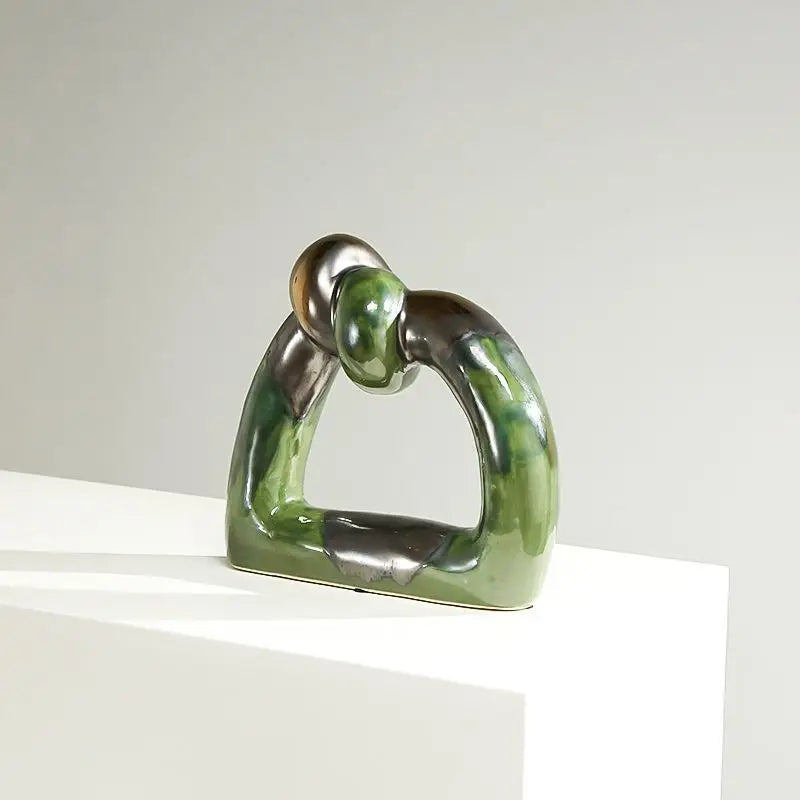 Green and silver abstract knot ceramic sculpture with hollow geometric design, perfect for modern home decor and adding a splash of color.