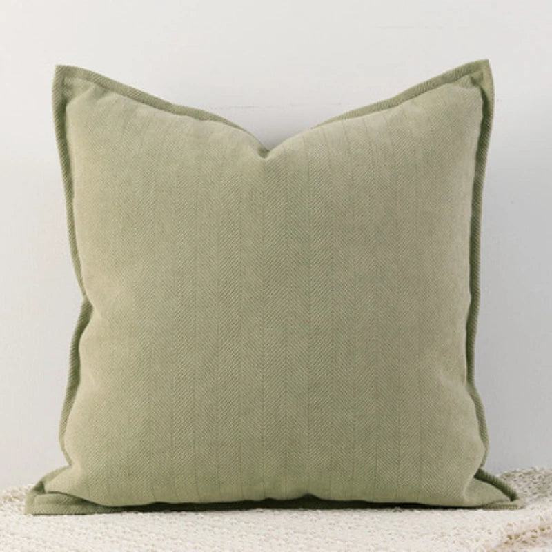 A green Nordic cushion cover placed over a couch, showcasing its delicate and cozy texture.