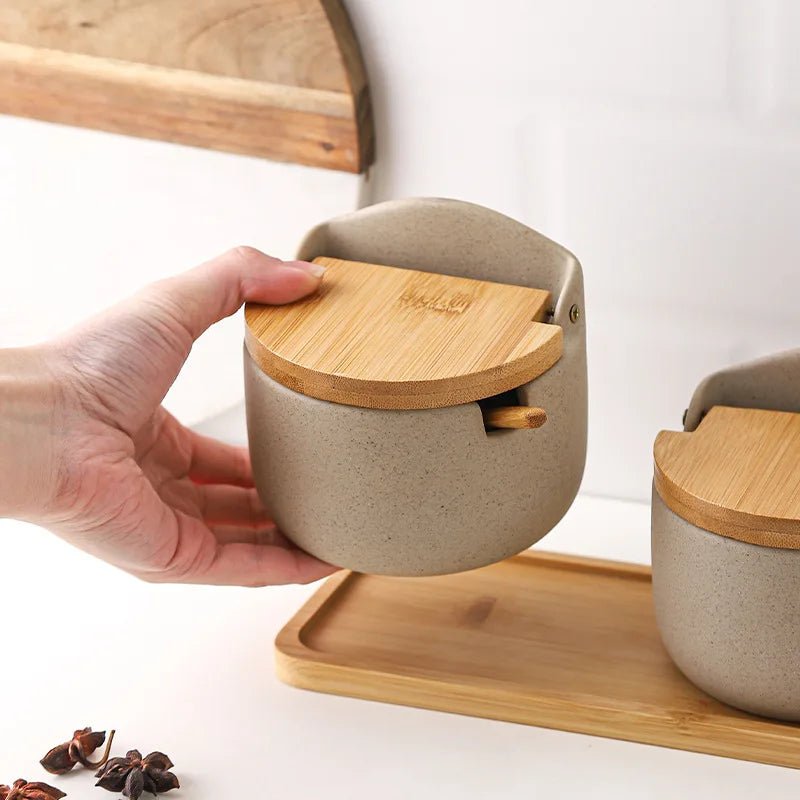 A hand touching a set of ceramic seasoning jars with wooden lids