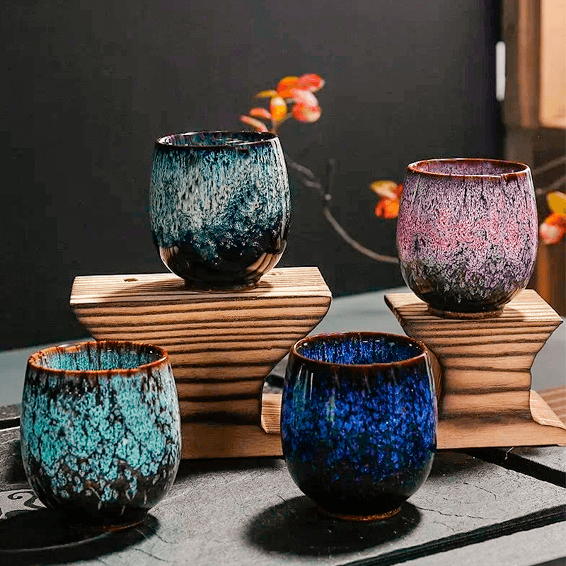 handcrafted ceramic cups with unique textured glazes in green, purple, teal, and blue colors