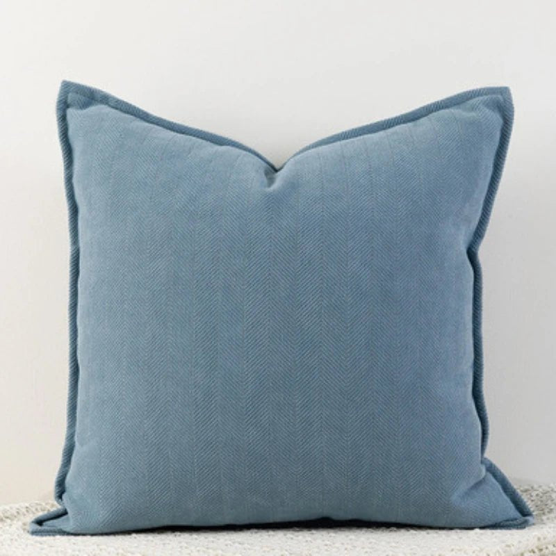 A haze-blue Nordic cushion cover placed over a couch, showcasing its delicate and cozy texture.