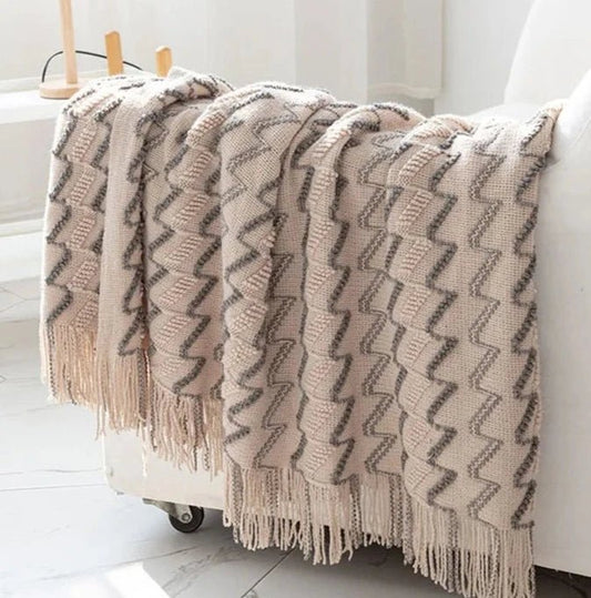 A khaki luxurious soft acrylic blanket draped over a couch, showcasing its soft and cozy texture.