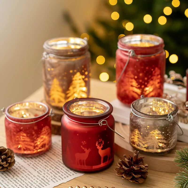 Christmas glass candle holders with etched winter scenes of pine trees and reindeer.