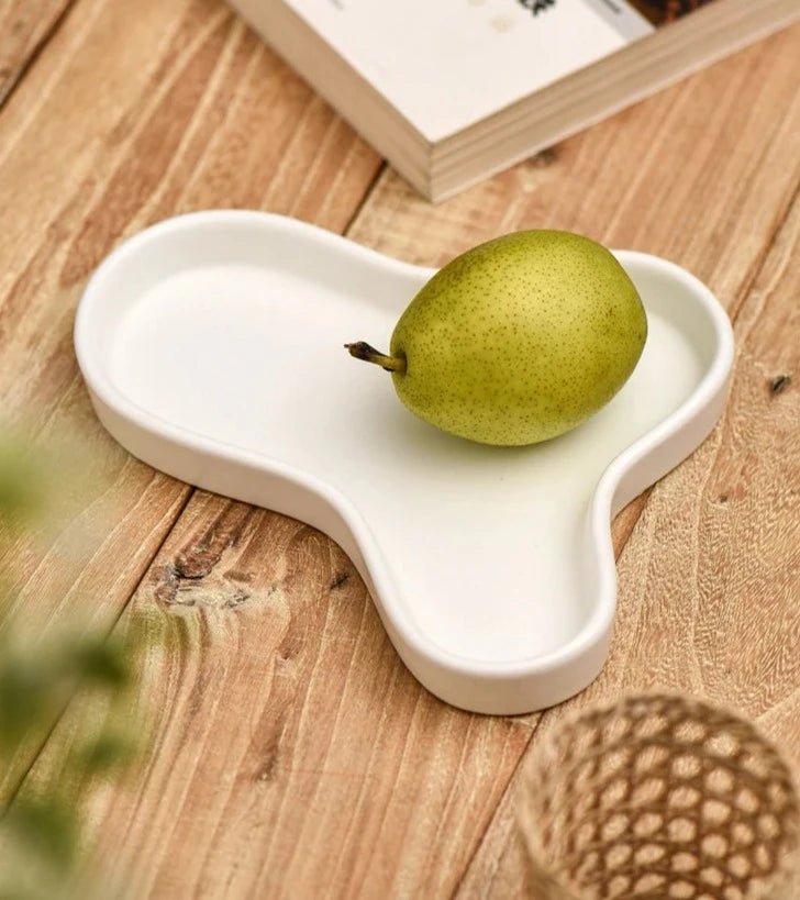 Minimalist irregular ceramic tray used as a coffee table centerpiece and jewelry storage.