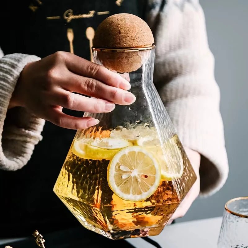 A person holding a stylish Nordic Glass Pitcher filled with water and slices of lemon