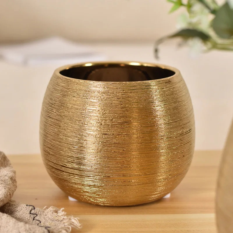 A brushed golden ceramic round vase with smooth curves, perfect for adding a touch of luxury to any home décor.