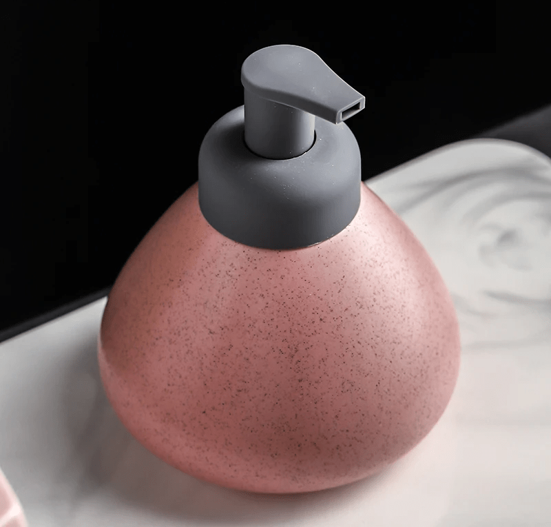 A pink ceramic soap dispenser with a sleek design, ideal for modern bathroom decor.