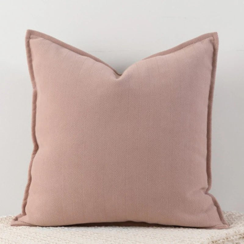 A pink Nordic cushion cover placed over a couch, showcasing its delicate and cozy texture.