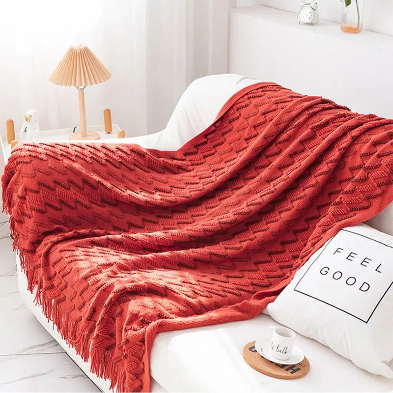 A red luxurious soft acrylic blanket draped over a couch, showcasing its soft and cozy texture.