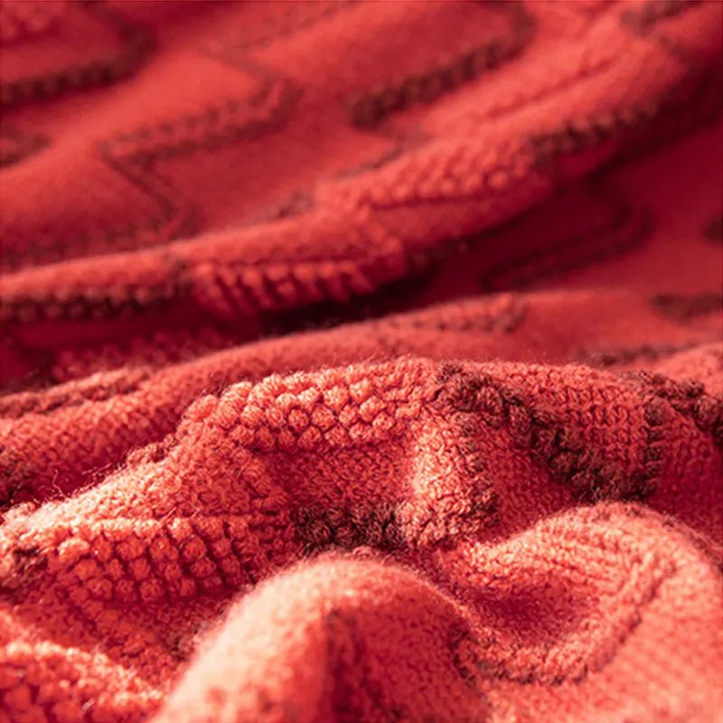 A red luxurious soft acrylic blanket draped over a couch, showcasing its soft and cozy texture.