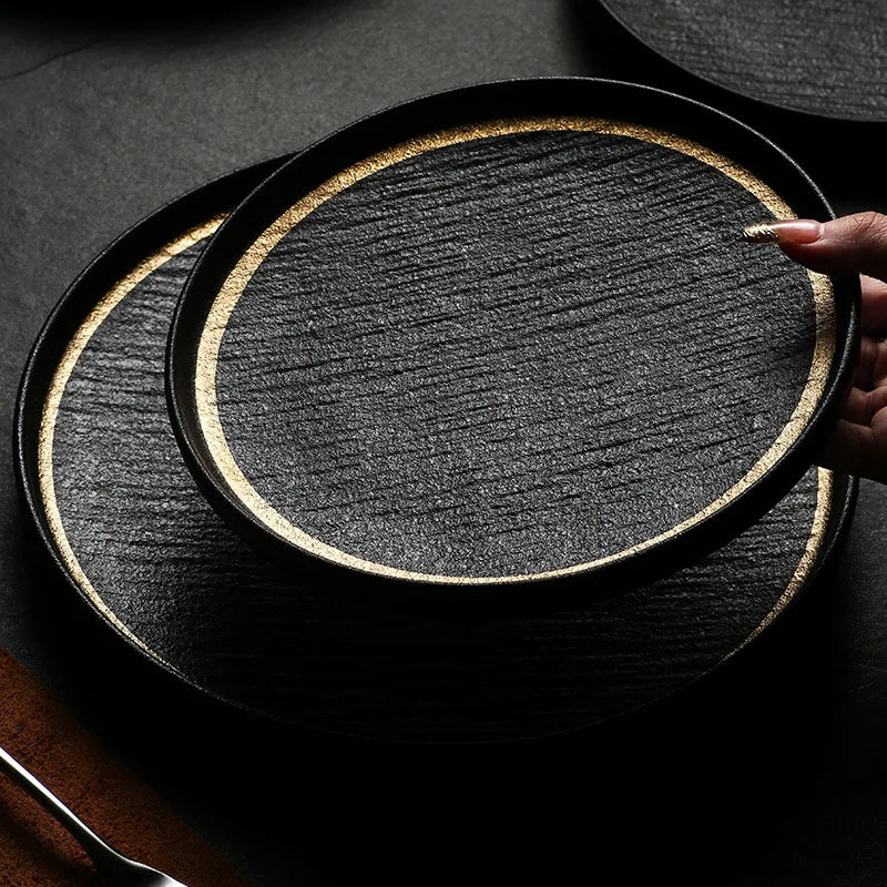 A black slate plate with a gold rim, perfect for serving appetizers or desserts.