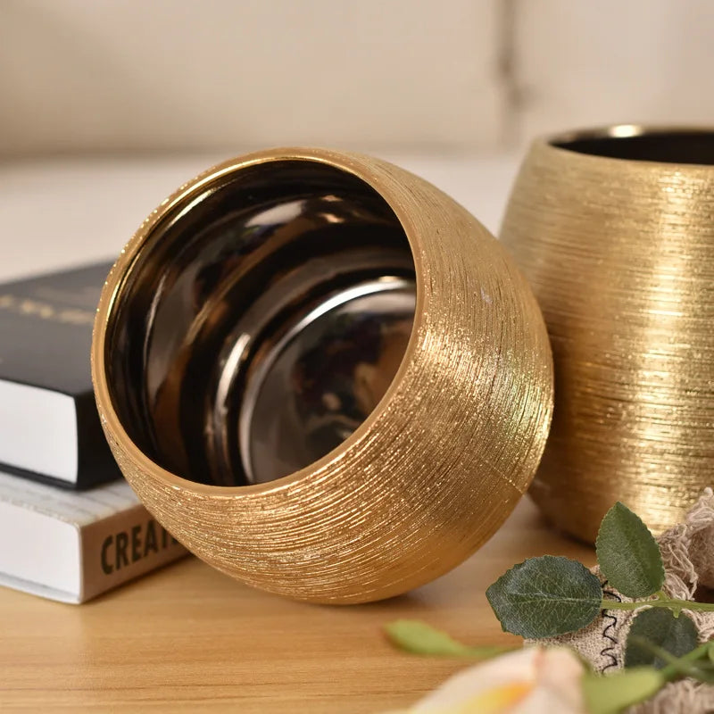 A brushed golden ceramic round vase with smooth curves, perfect for adding a touch of luxury to any home décor.