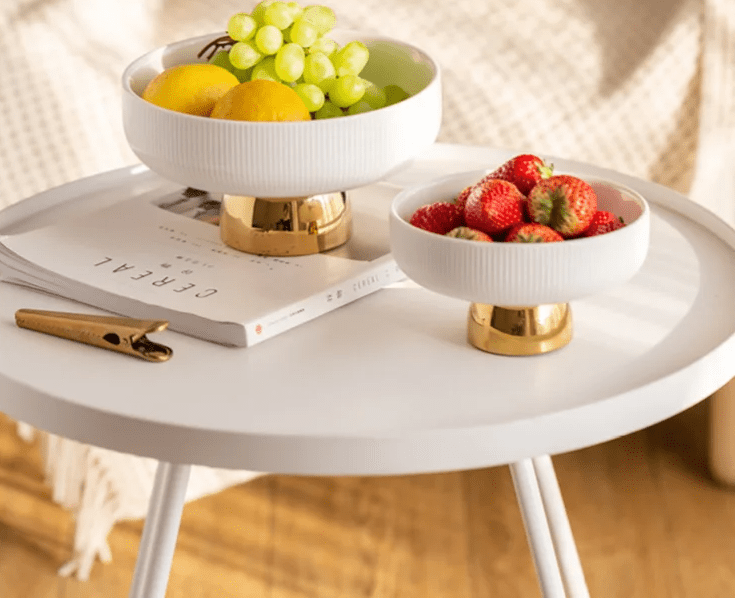 Two ceramic fruit bowls filled with strawberries, grapes, and an orange