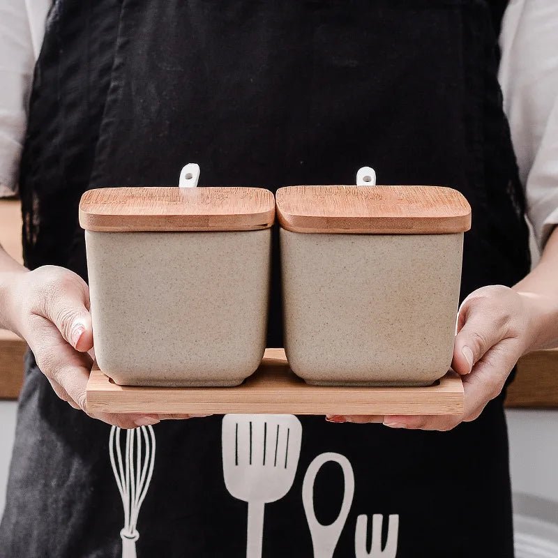 Person holding two sets of ceramic seasoning jars with wooden lids